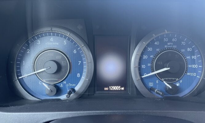 Dashboard instrument cluster with tachometer on left, speedometer on right, center display shows odometer 129,005 mi.