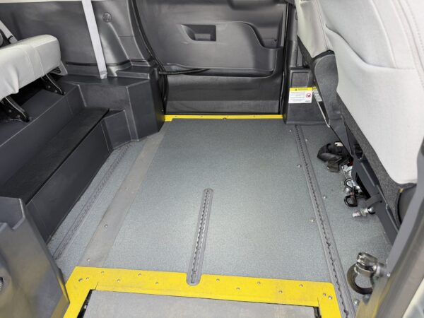 IMG_3383 Interior of a bus accessibility area with floor tracks for a wheelchair, a yellow threshold strip, and side benches folded along the walls