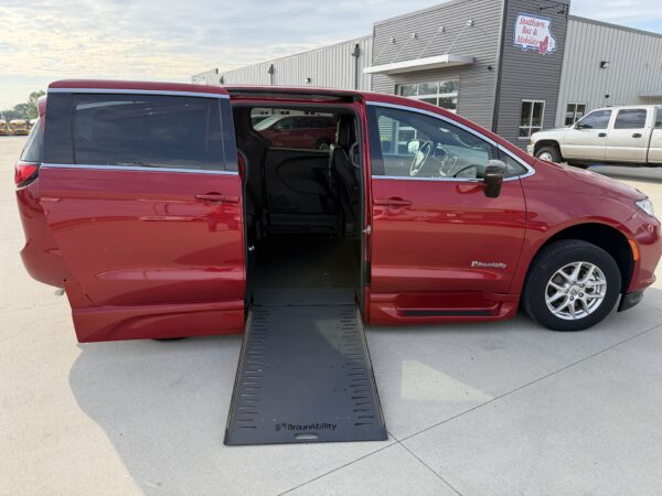 IMG_3473 Red wheelchair-accessible van with a lowered ramp extending from side door at a dealership or service center.