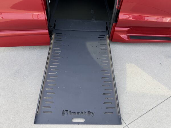 IMG_3474 Red van with a black BraunAbility wheelchair ramp extended onto a paved surface for access.