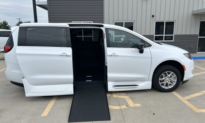 White minivan with lowered floor and a deployed wheelchair ramp for accessible entry.