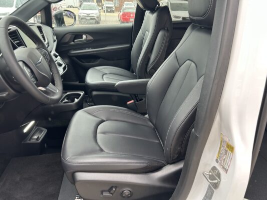 Interior of a car showing black leather seats with white stitching, driver seat, steering wheel, and center console.