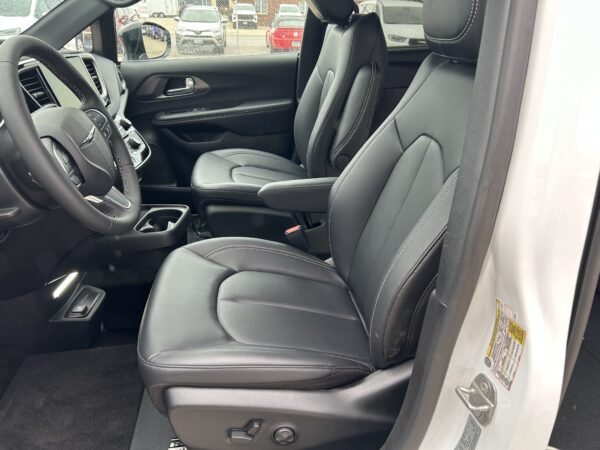 Interior of a car showing black leather seats with white stitching, driver seat, steering wheel, and center console.