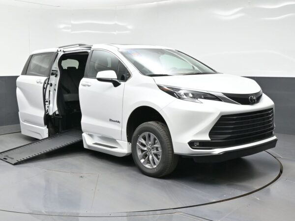 White Toyota minivan with a lowered side ramp extended for wheelchair access, doors open in a studio setting