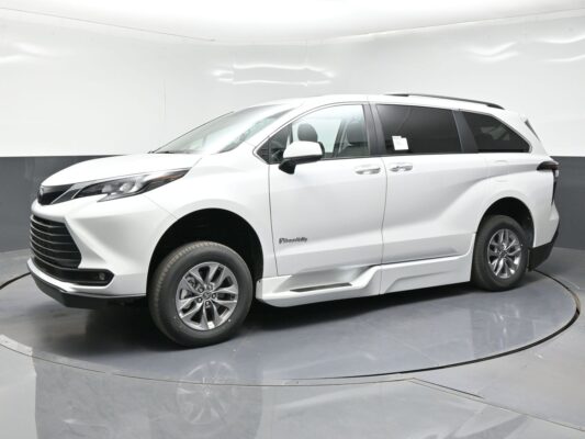 Front three-quarter view of a white BraunAbility wheelchair-accessible minivan in a studio setting.