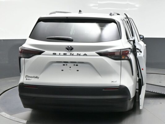 Rear view of a white Toyota Sienna minivan showing BraunAbility branding; sliding side door is open on the right side.