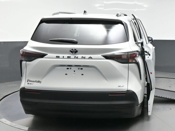Rear view of a white Toyota Sienna minivan showing BraunAbility branding; sliding side door is open on the right side.