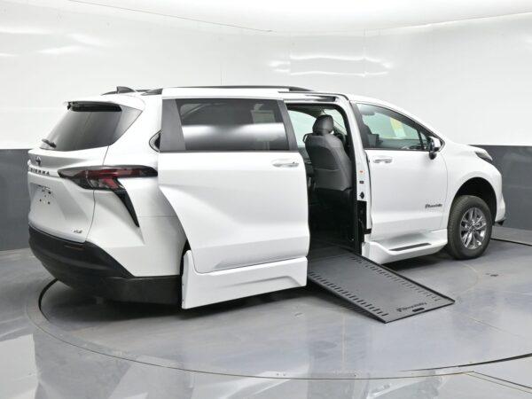 White minivan with the side door open and a lowered wheelchair ramp ready for boarding.