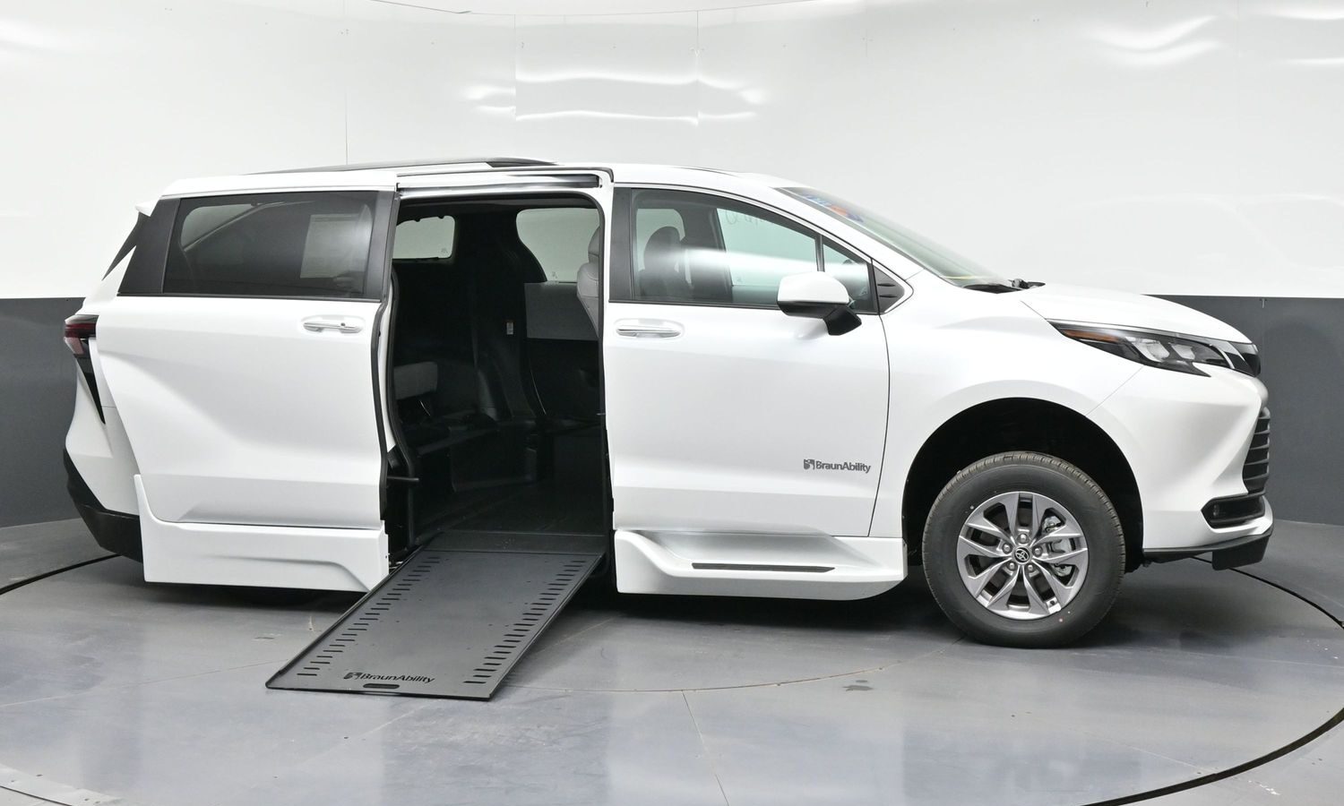 White minivan with its side door open and a lowered ramp, ready for a wheelchair user (BraunAbility).