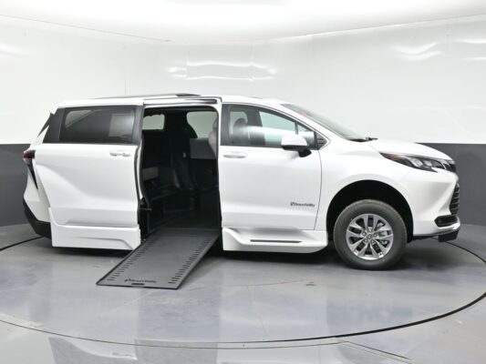 White minivan with its side door open and a lowered ramp, ready for a wheelchair user (BraunAbility).