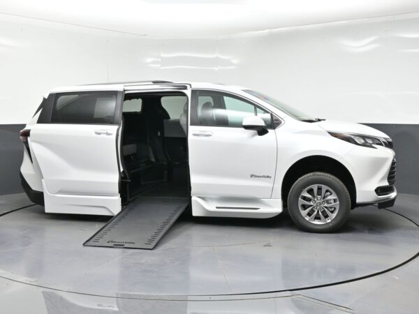 White minivan with its side door open and a lowered ramp, ready for a wheelchair user (BraunAbility).