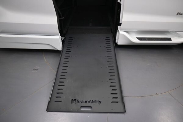Wheelchair access ramp extended from a white BraunAbility van, ready for a person to roll onto.