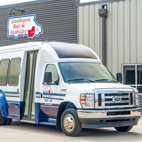 White and blue shuttle bus parked outside a gray metal building with a 'Southern Bus & Mobility' sign above it