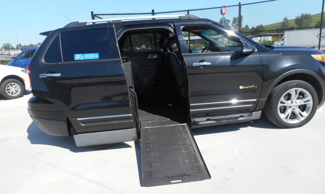 Black SUV with a deployed wheelchair ramp extending from the open rear door for accessibility uptake. BraunaAbility badge visible on the side.