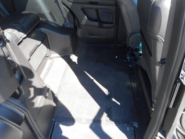 Rear passenger area of a car with the floor exposed, showing rails and empty floor space between seats.