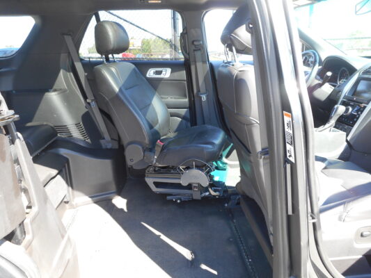Interior of a SUV with black leather seats and a wheelchair lift base installed on the floor between the front seats.