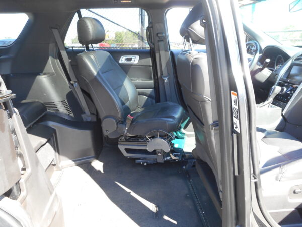 Interior of a SUV with black leather seats and a wheelchair lift base installed on the floor between the front seats.