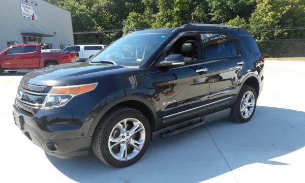 Black SUV (Ford/agency badge) with BraunAbility logo, parked in a dealership lot with other trucks and a building in the background
