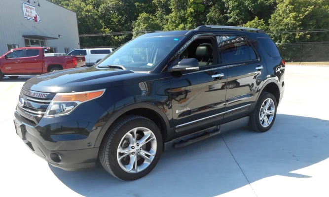 Black SUV (Ford/agency badge) with BraunAbility logo, parked in a dealership lot with other trucks and a building in the background