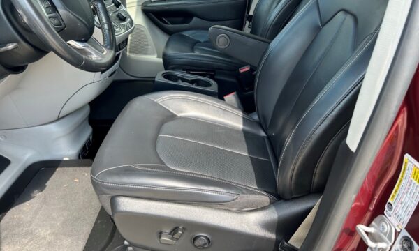Front interior of a car with black leather seats, steering wheel, and center console with cup holders