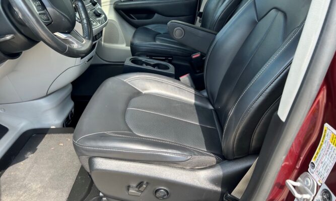 Front interior of a car with black leather seats, steering wheel, and center console with cup holders