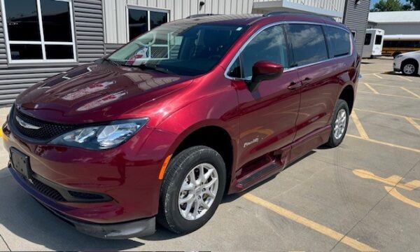 Red Chrysler Pacifica minivan parked in a dealership lot, three-quarter front view.