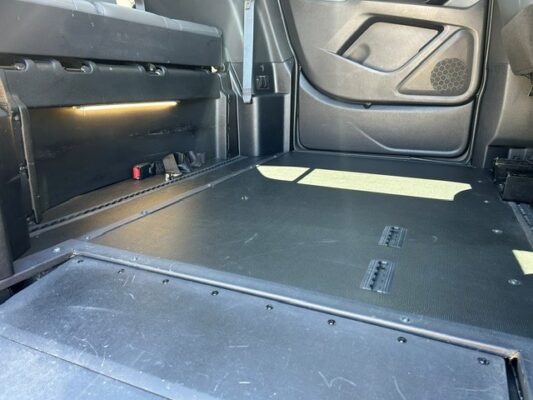 Cargo area of a vehicle showing a flat floor and folded rear seats, with side panel and door interior visible on the right.