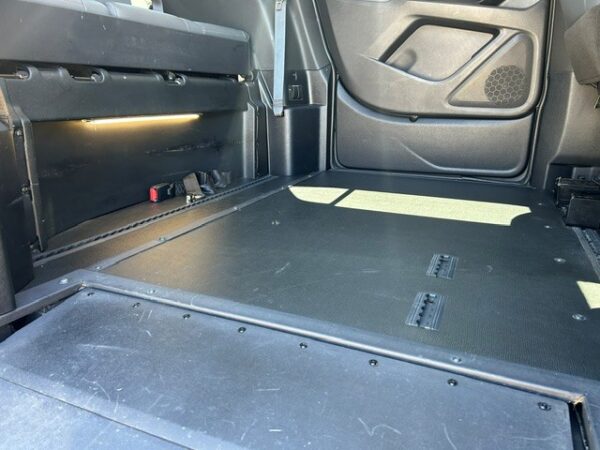 Cargo area of a vehicle showing a flat floor and folded rear seats, with side panel and door interior visible on the right.