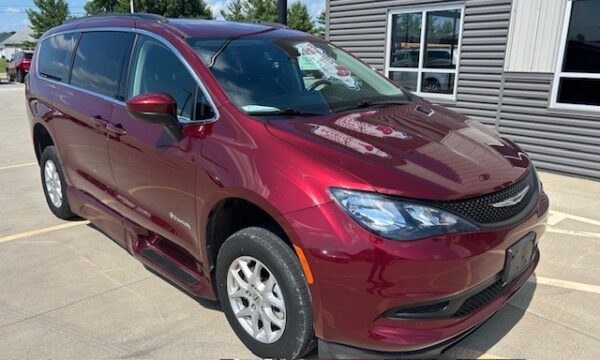 Maroon minivan parked in a dealership lot, angled front-right view showing chrome grille and headlights