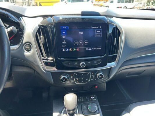Center-console dashboard with touchscreen displaying radio 1120 AM and climate controls below the screen in a modern car interior.