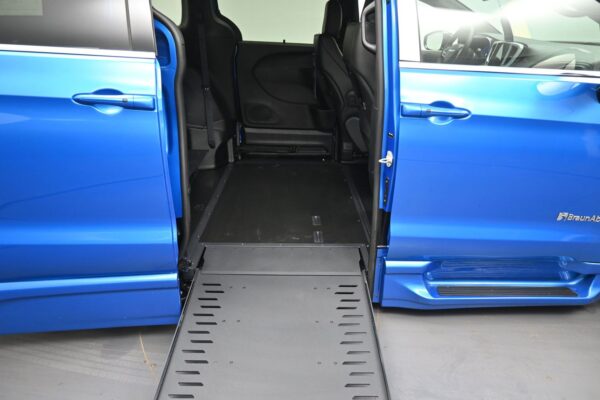 Blue wheelchair-accessible van with ramp extended, showing interior and seating ready for boarding.