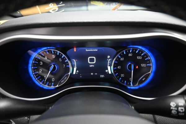 Car instrument cluster with blue-lit tachometer (left), speedometer (right), and center display showing 0 MPH.