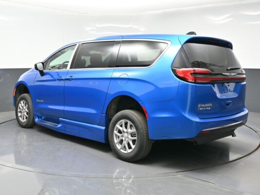 Blue Chrysler Pacifica minivan photographed from rear three-quarter view in a studio, showing alloy wheels and chrome window trim.