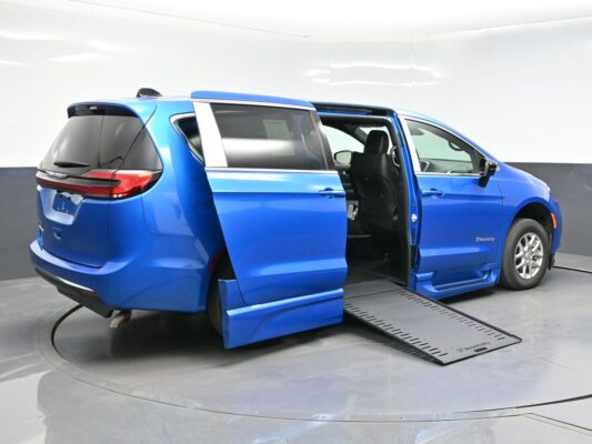 Blue minivan with both side doors open and a deployed side ramp for wheelchair access.