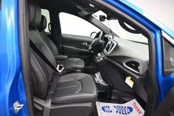 Interior of a blue car: black leather front seats, steering wheel, and dashboard visible from the open driver-side door