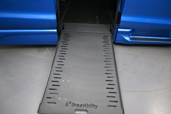 Blue van with a black BraunAbility wheelchair ramp extended from the side, ready for access.