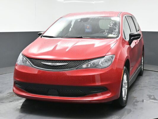 Red Chrysler sedan photographed from a front-left angle, with rain droplets on the surface and a dark grille and headlights visible.