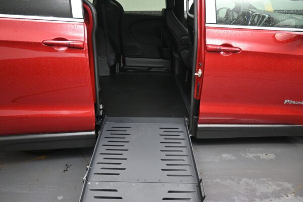 Red minivan with a lowered metal ramp extending from the side door, ready for wheelchair access.