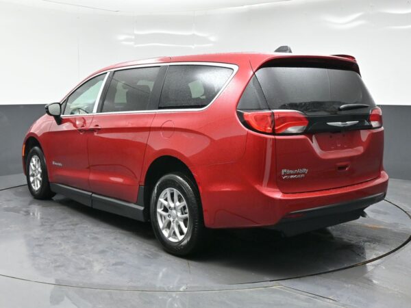 wav-2C4RC1CG9TR284610-4 Three-quarter rear view of a red BraunAbility Voyager minivan photographed in a studio, showing rear hatch and tinted windows.