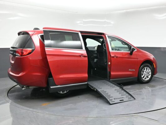 Red minivan with a lowered side ramp for wheelchair access, interior seating visible from the open sliding door