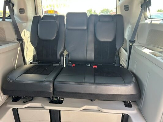 Rear row of black leather seats in a vehicle, two seats with headrests, showing seat belts and cupholders nearby.