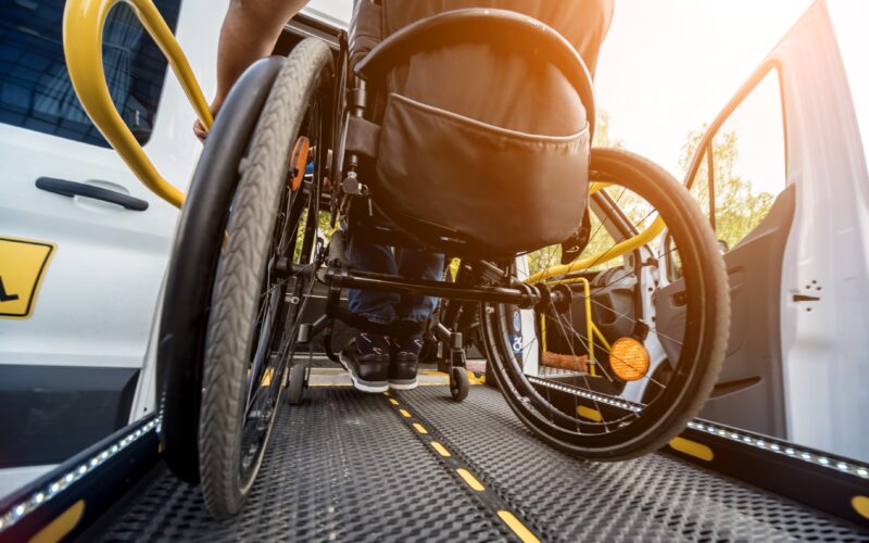 A man in a wheelchair on a ramp of a specialized vehicle for people with disabilities.