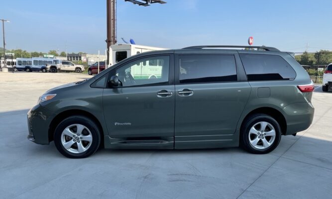 Green BraunAbility wheelchair-accessible minivan parked in a concrete lot, side view with sliding doors visible.