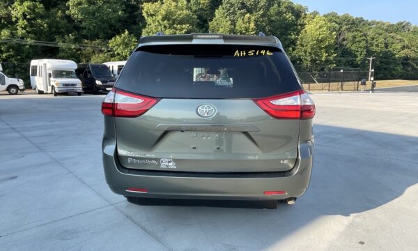 IMG_0389 Rear view of a gray Toyota Sienna minivan parked in a lot, with a BraunAbility sticker on the lower left bumper and a yellow ID number on the rear window reading AH5146.