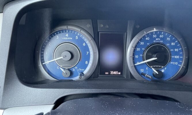 Instrument cluster of a car with blue-dial gauges: tachometer on the left, speedometer on the right, and a central digital odometer reading 35,465 miles.