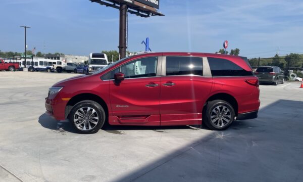 IMG_0440 Red minivan (BraunAbility) parked in a lot, side view showing accessibility branding and lowered side step.