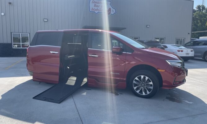 Red wheelchair-accessible minivan with its ramp deployed, parked outside a mobility shop labeled Southern Bus & Mobility