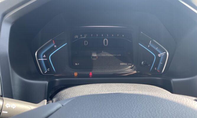 Digital car dashboard: gear D, speed 0, outside temp 76°F, odometer 8,552 miles; tire pressure low warning illuminated; fuel gauge near E.