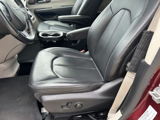 Front car cabin featuring black leather seats with white stitching, center console, and cupholders in view