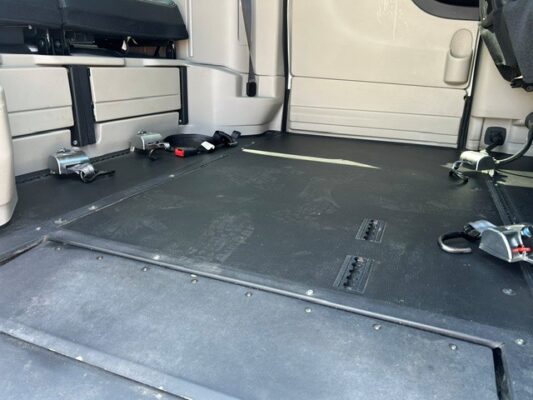 Truck cargo area with a black rubber floor, side tie-down anchors, and latches along the walls.